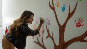 estudante do projeto comunitário escreve seu nome na árvore desenhada no Marista Escola Social