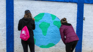 Duas estudantes estão pintando a parede da instituição